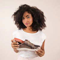 Holding an Aetrex Premium Memory Foam orthotic beside the sneaker it is going into