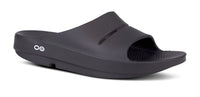 OOFOS OOahh Slide 1100 in black, angled view showing the cupped heel and OOfoam strap
