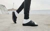 OOFOS OOahh Slide 1100 in black, detail of the strap and footbed junction